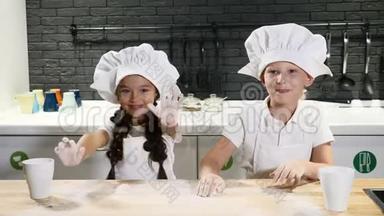 厨师小子。 两个戴厨师帽的孩子玩面团。 在家庭厨房玩得开心。 准备意大利面。 4k
